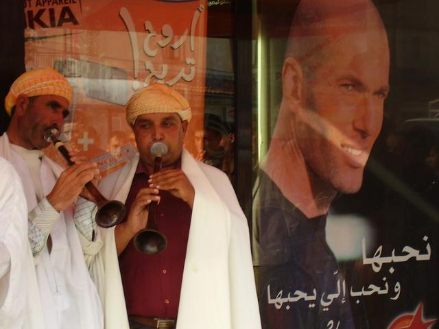 Two idebbalen playing in a street of Béjaïa. On the back, Zinedine Zidane's picture is in an advertisement for Ooredoo Algeria