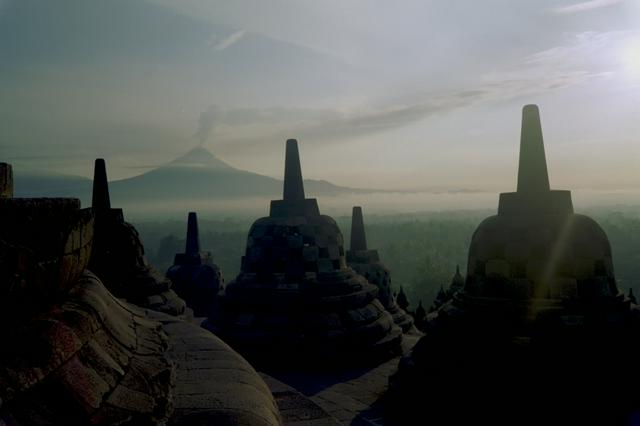 Sunrise at the stupas of Borobudur with steaming Mount Merapi in the background