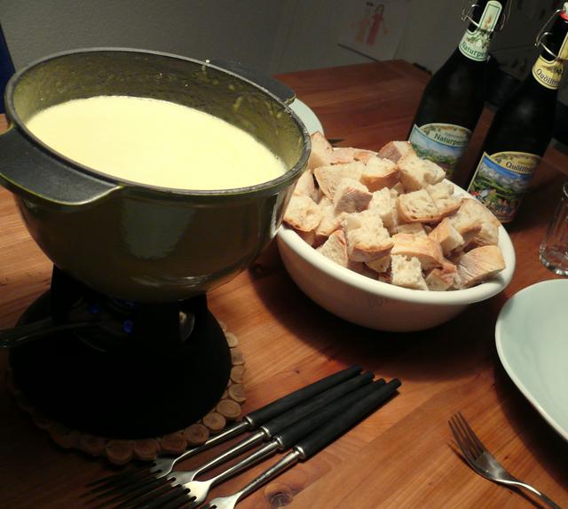 A pot of Fondue, pieces of bread and fondue forks