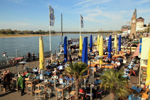 The riverbank is filled with cafe tables in Düsseldorf
