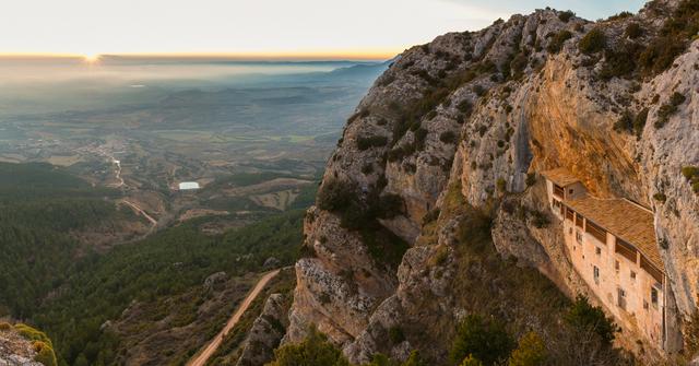 Sunset view of the Ermita de la Virgen de la Peña (Hermitage of the Virgin of the Rock), with the village of Aniés in the front; this hermitage, featuring elements from as far back as the 13th century, is accessible only on foot