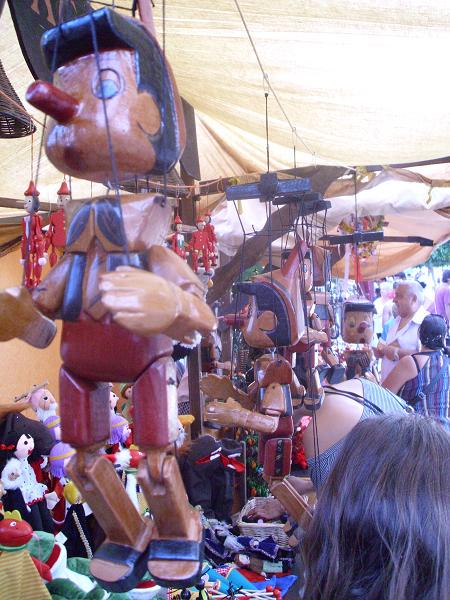 The numerous stalls are alive with colors and patterns. Above are recognizable wooden figures, hand crafted from the skilled merchants.