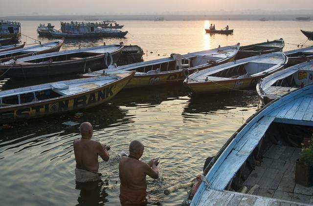 Men praying between boats in the Ganges