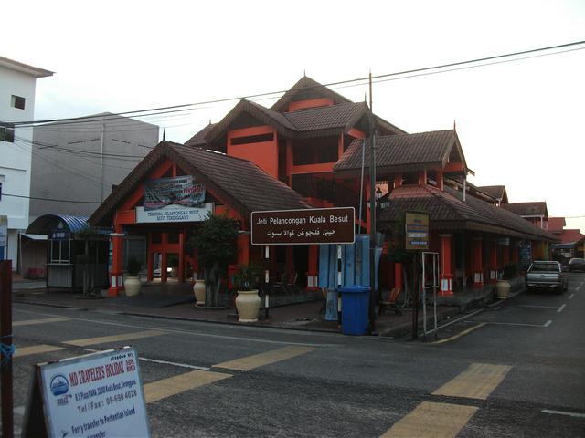 Entrance to the Kuala Besut Tourist Jetty, with its traditional-Terengganu-palace-style roof, showing the Malay-language sign in Rumi (Roman letters) and Jawi (Arabic letters)