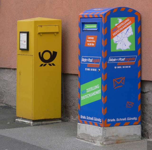 Letter boxes in Münnerstadt. At left is the yellow one of the former national postal service; the other one is a local service (still rather an unusual sight in Germany)