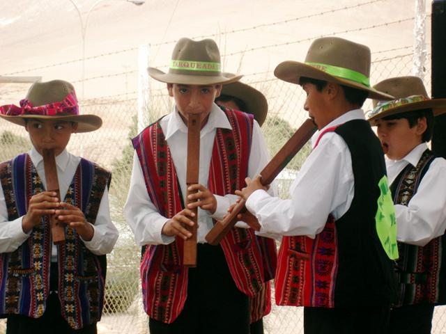 Colorfully dressed Quechua children playing the tarka, one of the traditional types of flute