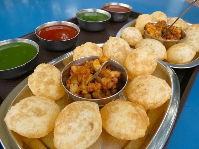 The hollow bread is punctured, opened and filled with vegetable mixture, and sauce