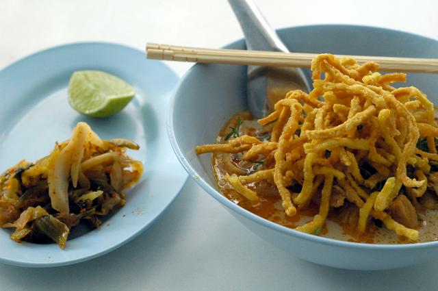 A bowl of khao soi kai, with pickled cabbage and lime to add to taste, in Chiang Rai