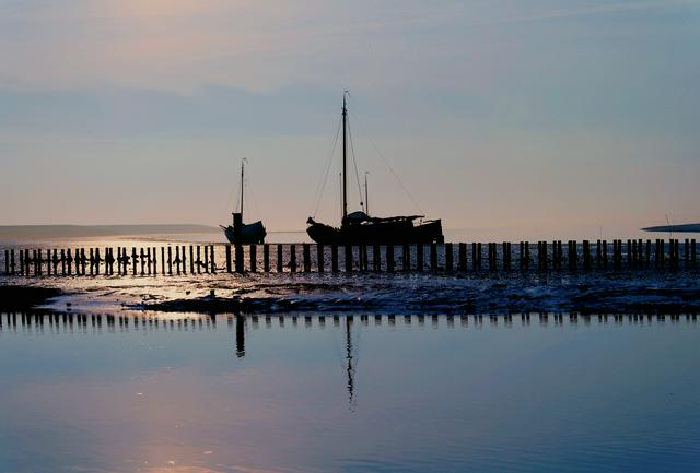 Boats moored off the coast of Terschelling during low tide.