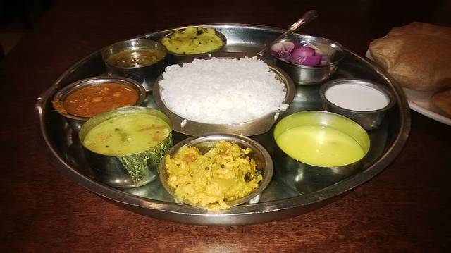 The Mumbai lunch consists of white rice, vegetable fries, dhal fries, onion, yoghurt and pooris. 