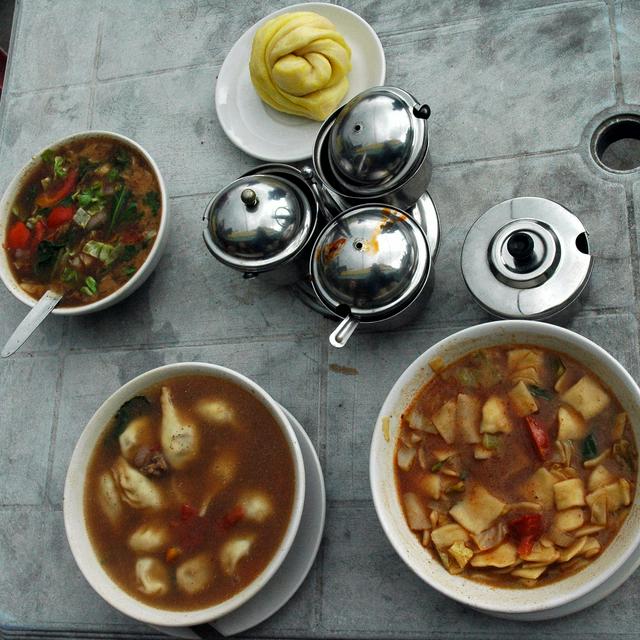 Clockwise from top: tingmo steamed bread, thenthuk noodle soup, momos in soup and vegetable gravy, with condiments in center