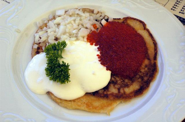 Bliny buckwheat pancakes with salmon roe (ikra), sour cream (smetana) and chopped onion