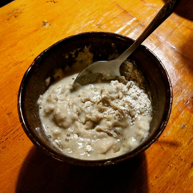 A bowl of tsampa in the process of having yak butter tea blended in