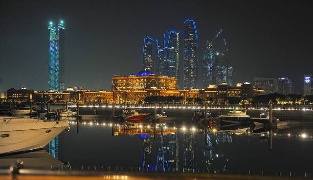 Abu Dhabi skyline at night showing Emirates Palace and Etihad Towers in the background.